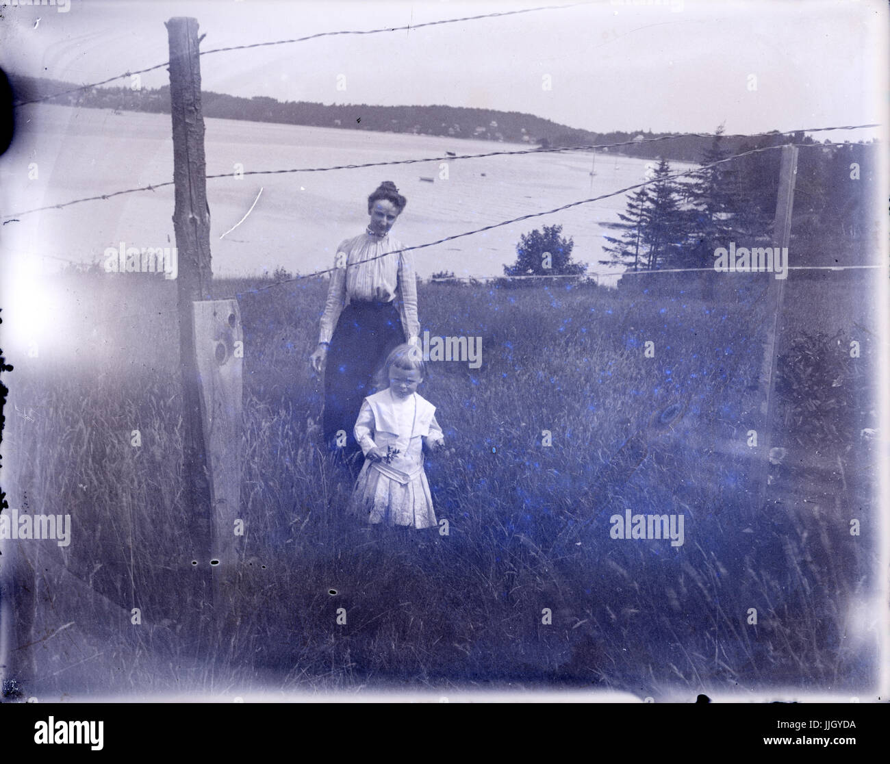 C1910 photographie antique, mère et fille sur une colline herbeuse à l'océan. Lieu inconnu, peut-être du Rhode Island, USA. SOURCE : photographie originale. Banque D'Images