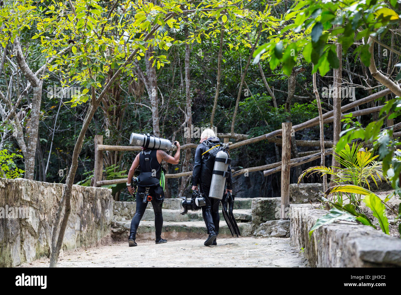 Les plongeurs transporter leur matériel en haut des escaliers après une plongée au Mexique's Dos Ojos Cenote. Banque D'Images