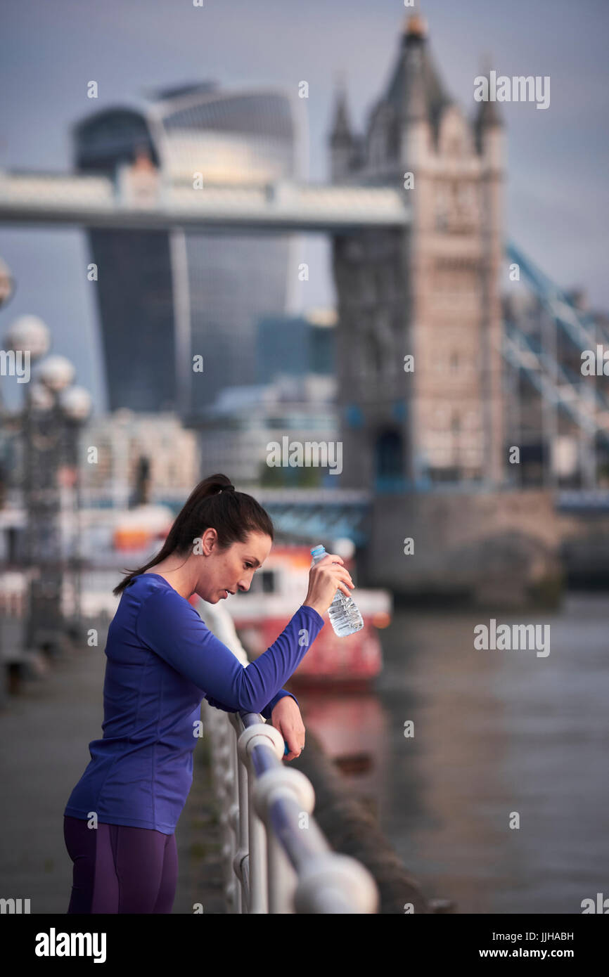 Une femme se reposant après une course le long de la Tamise à Londres. Banque D'Images