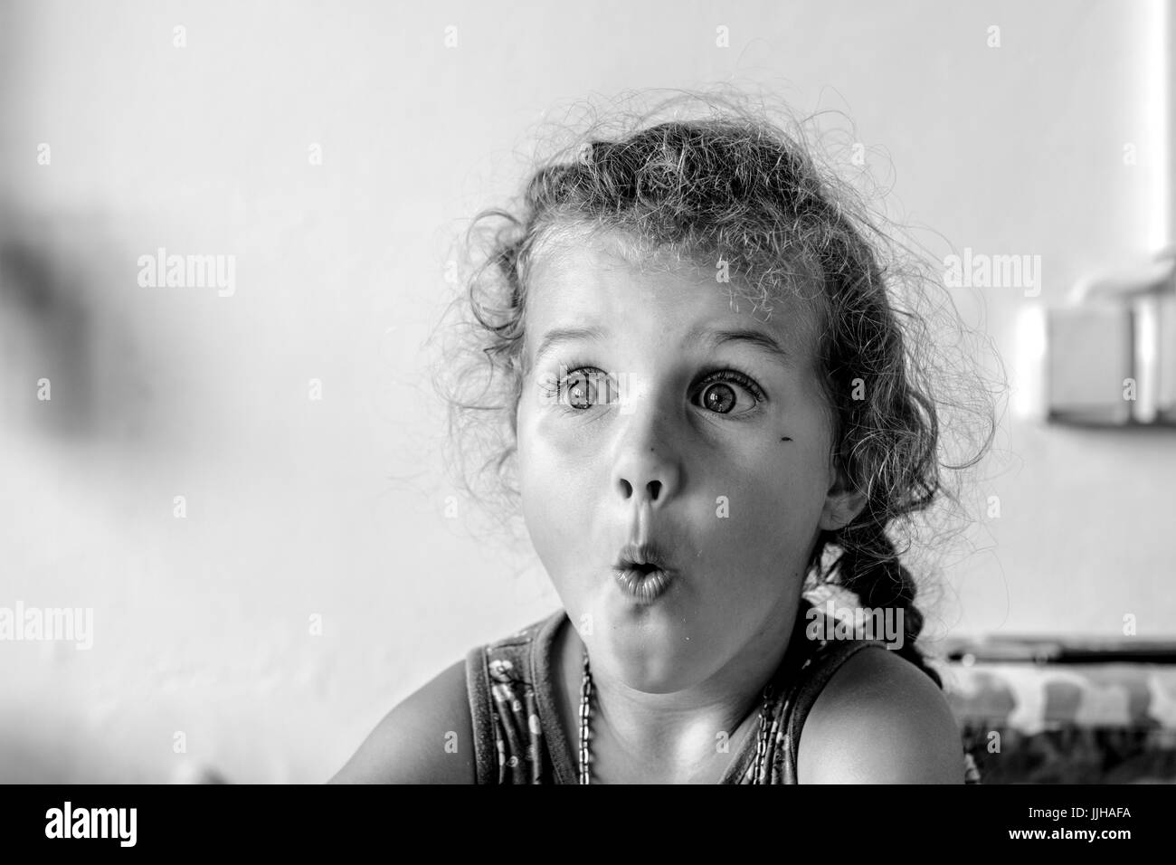 Photo noir et blanc avec surpris jeune fille aux cheveux bouclés regardant à droite Banque D'Images