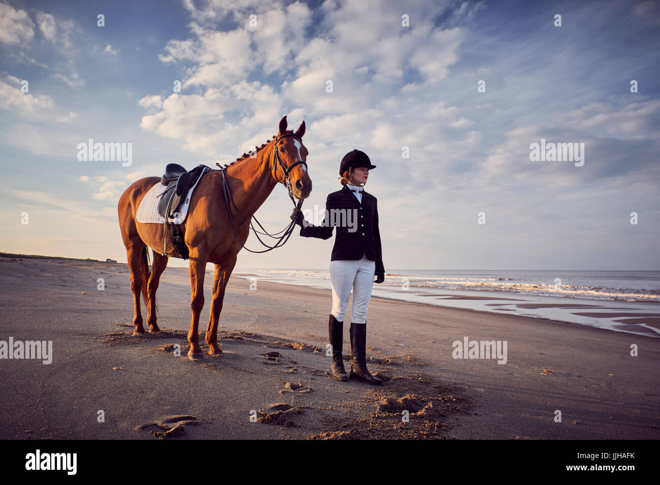 Une jeune femme debout avec son cheval sur la plage. Banque D'Images