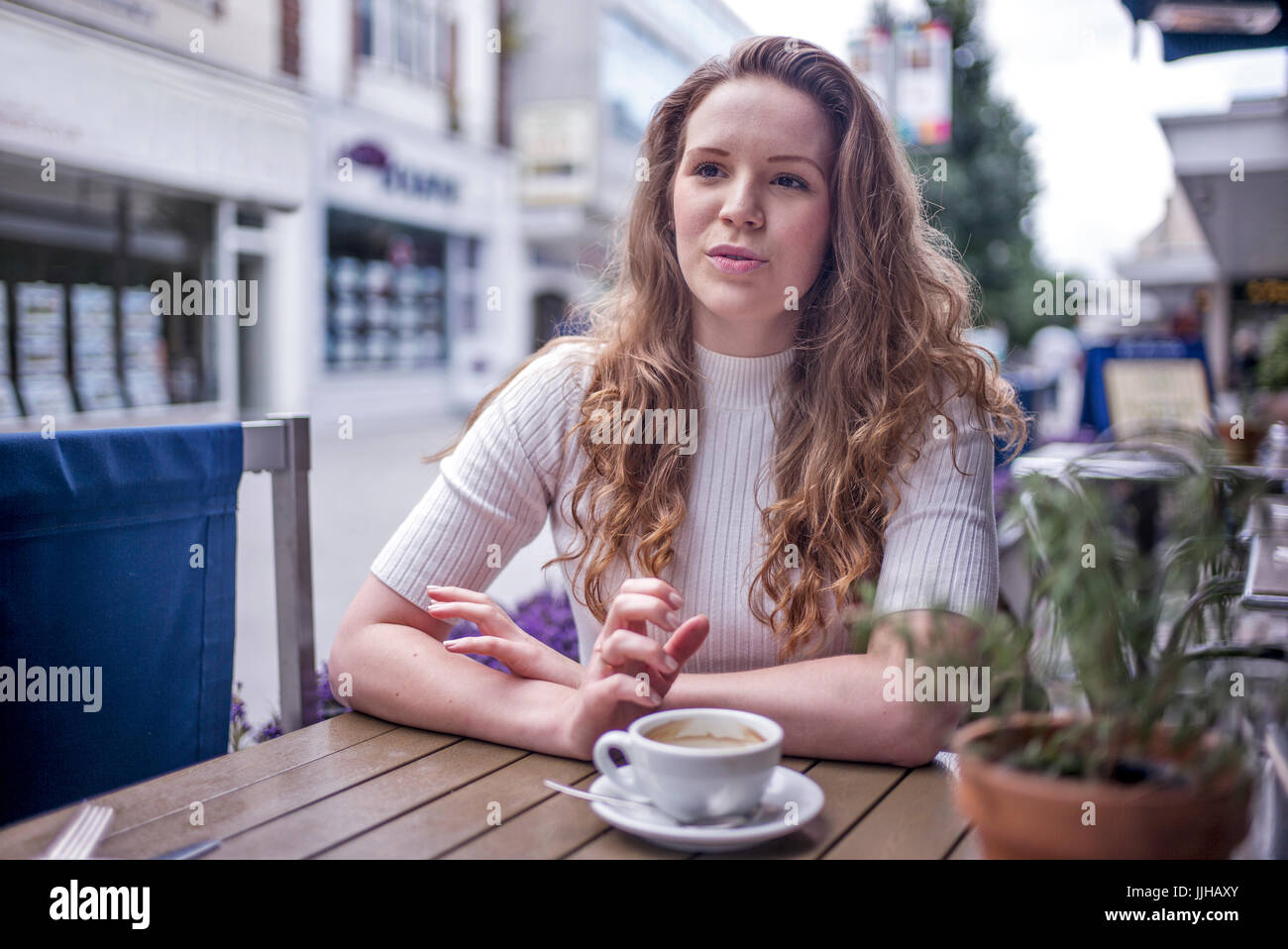 Une jeune femme assise à l'extérieur d'un café. Banque D'Images