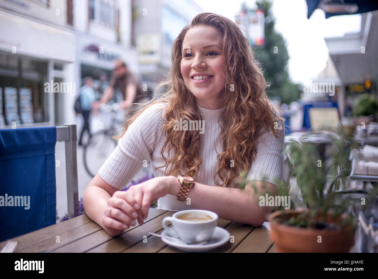 Une jeune femme assise à l'extérieur d'un café. Banque D'Images