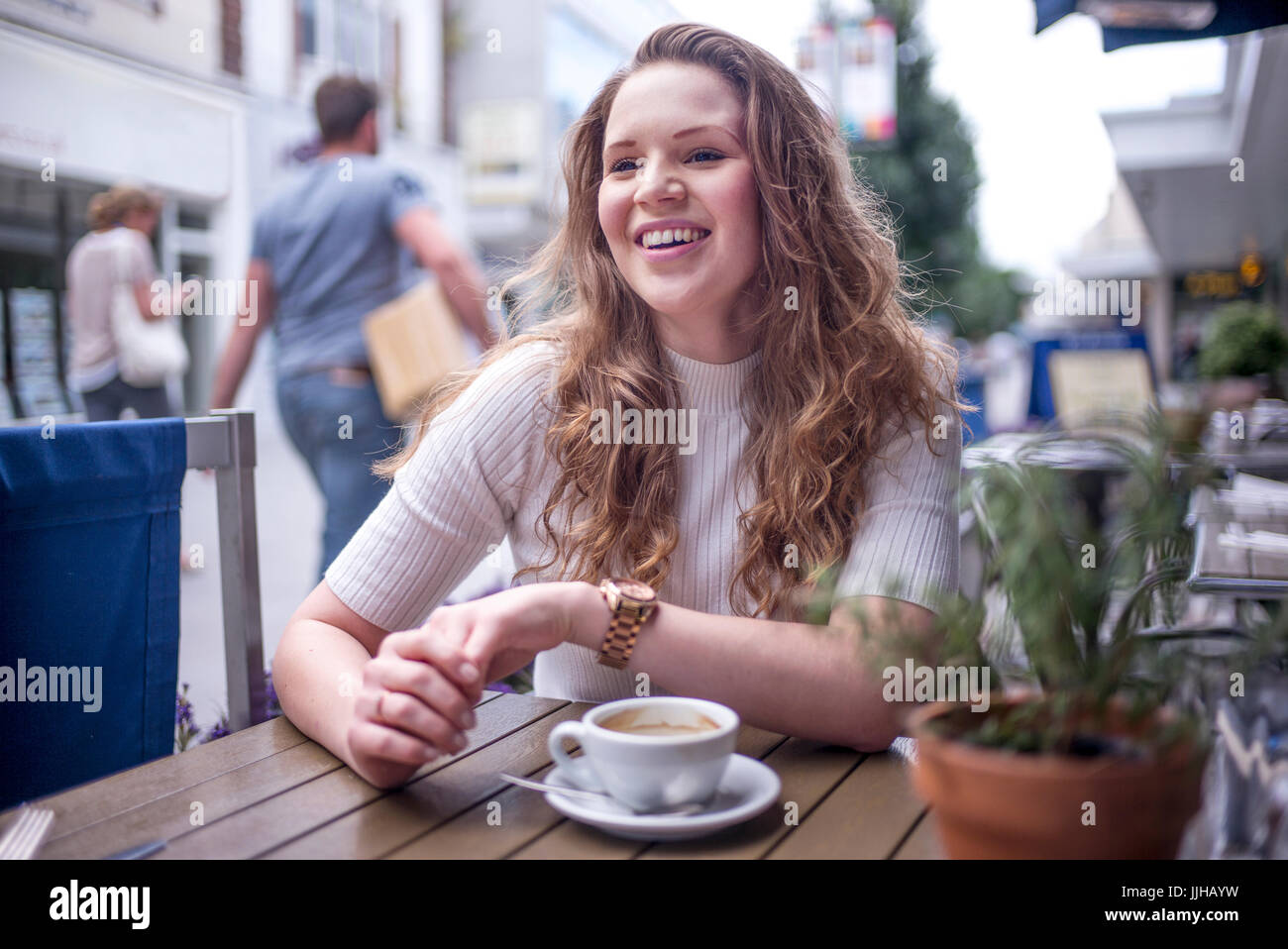 Une jeune femme assise à l'extérieur d'un café. Banque D'Images