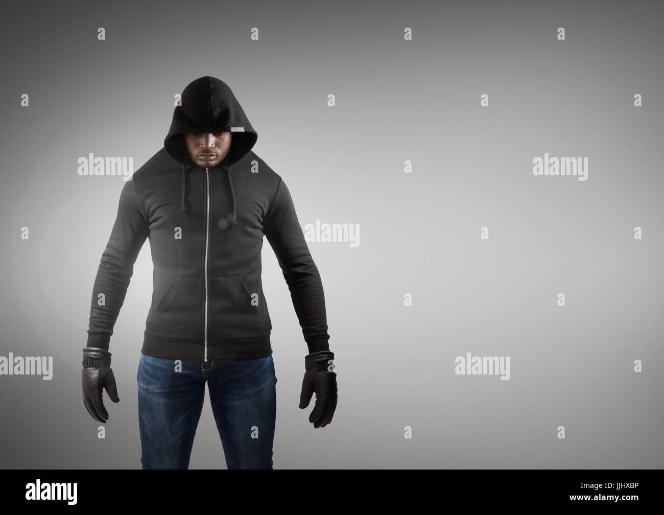 Hacker avec veste noire en face de l'arrière-plan gris Banque D'Images