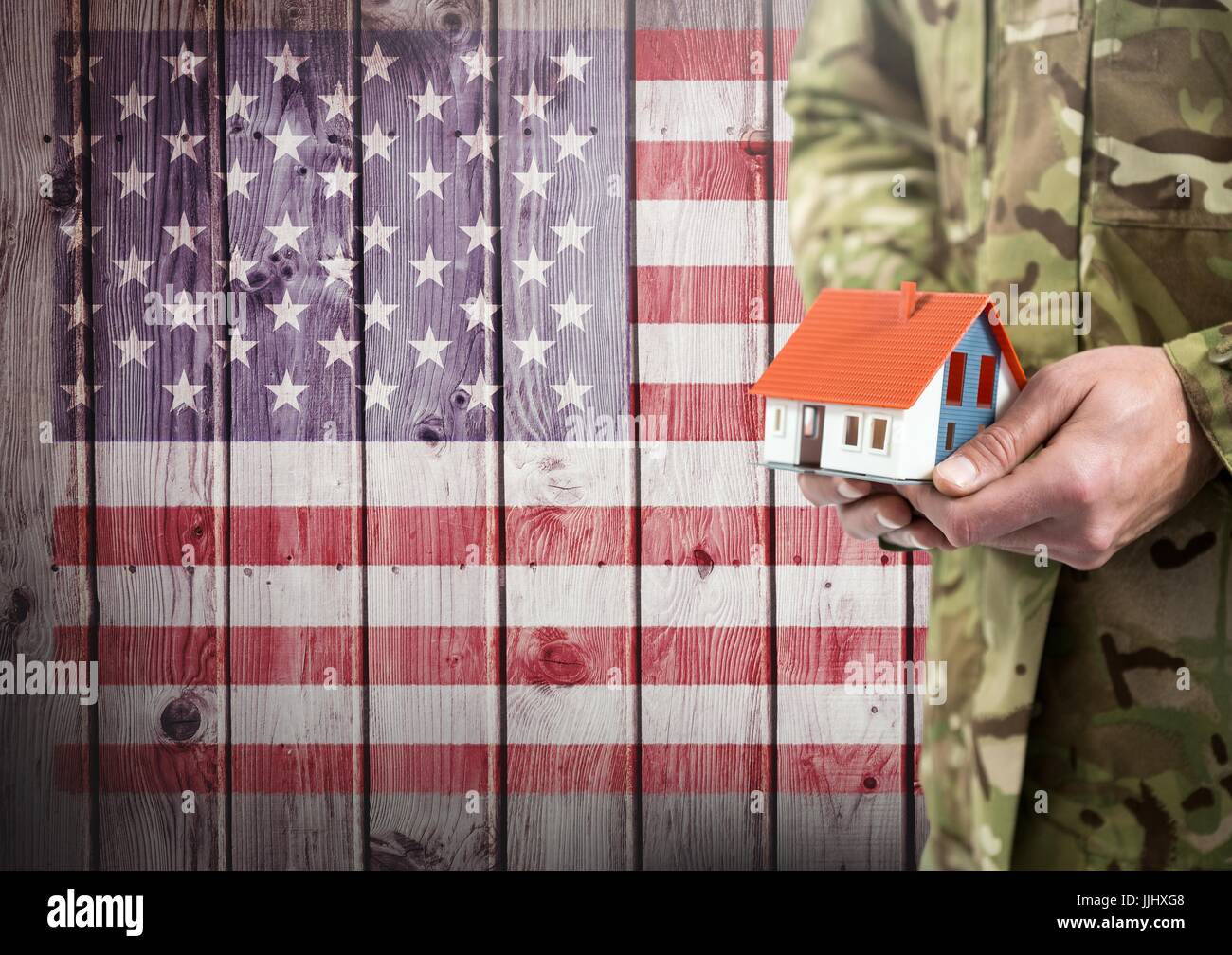 Close up of soldat tenant une petite maison en face du drapeau américain Banque D'Images