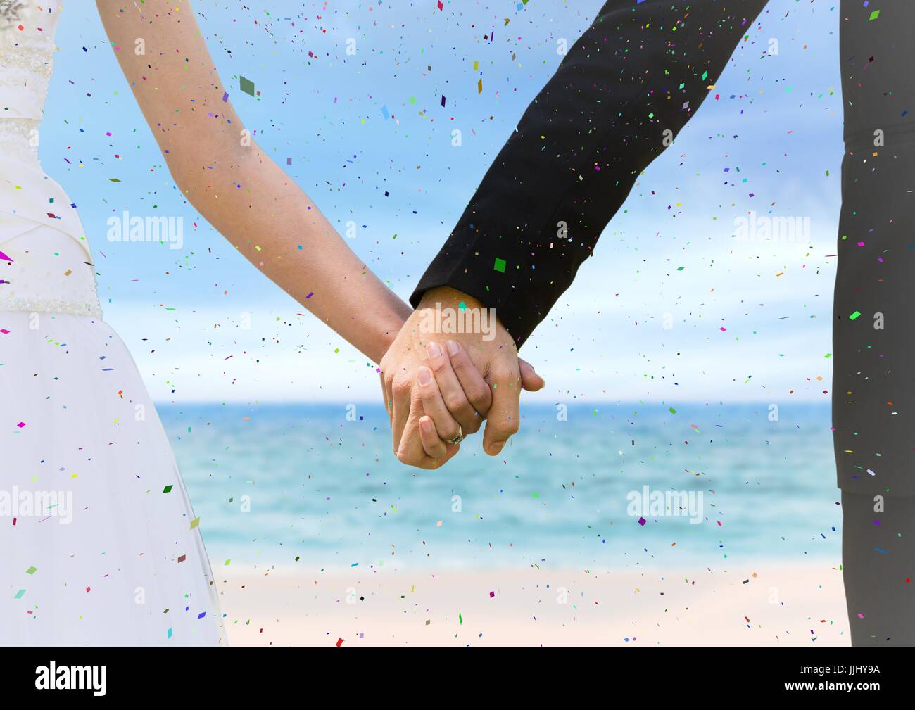 Confetti et Bride and Groom holding hands at blurry beach Banque D'Images
