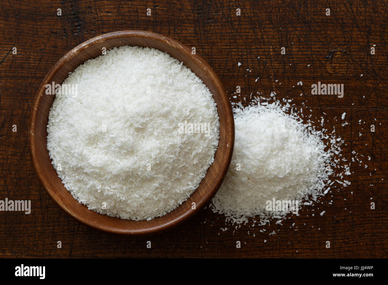Noix de coco desséchée dans le noir bol en bois isolé sur bois marron foncé à partir de ci-dessus. Récupérer la noix de coco. Banque D'Images