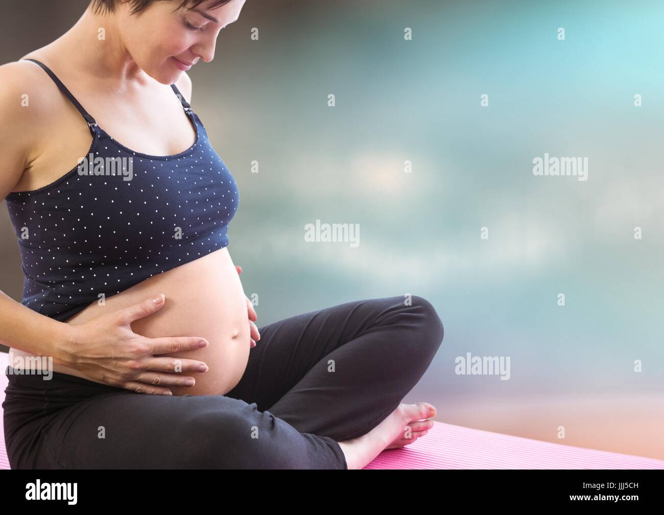Pregnant woman meditating contre floue fond marron bleu Banque D'Images