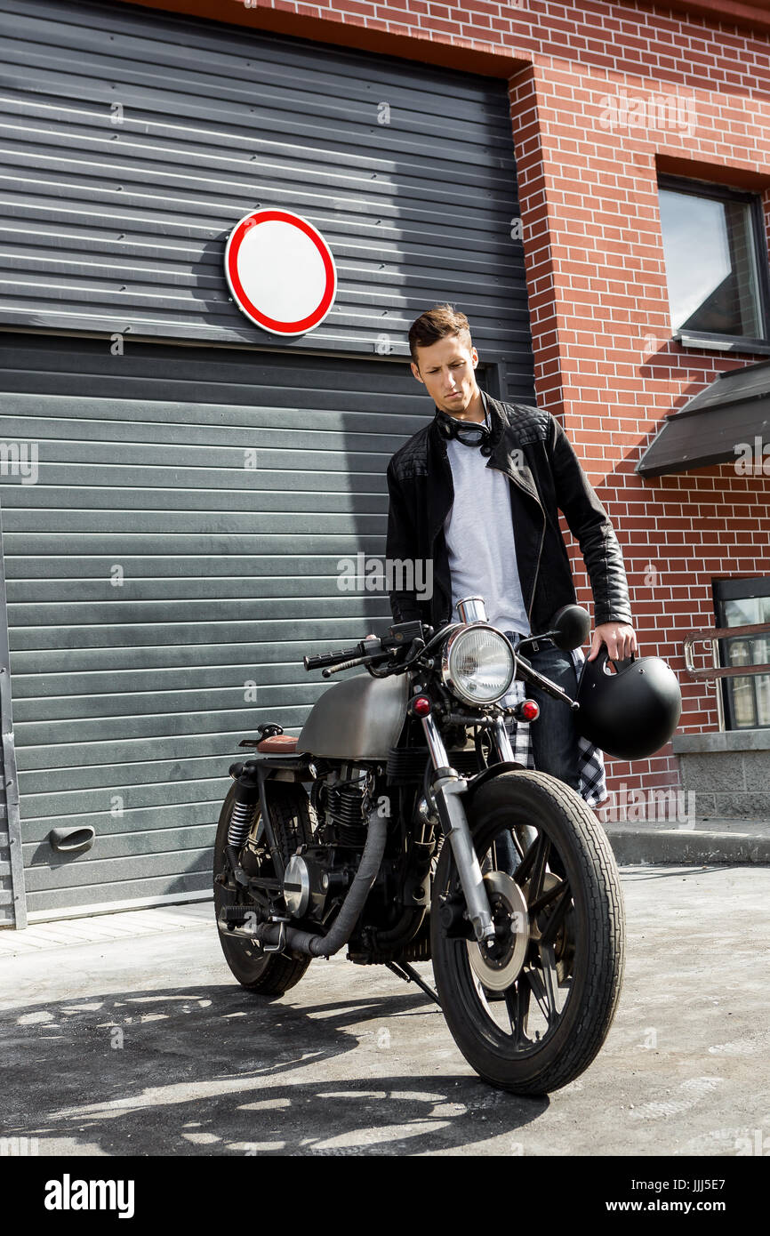 Beau jeune homme en noir veste biker jeans et aller à son style classique cafe  racer motorcycle portes industrielles comme arrière-plan. Custom Bike mad  Photo Stock - Alamy