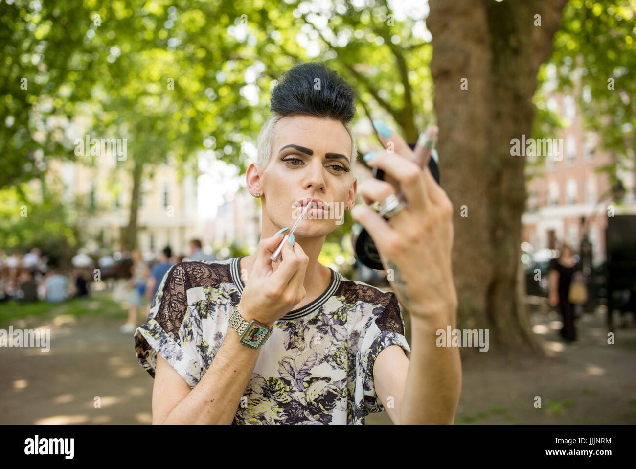 Un homme gay applique son maquillage. Banque D'Images