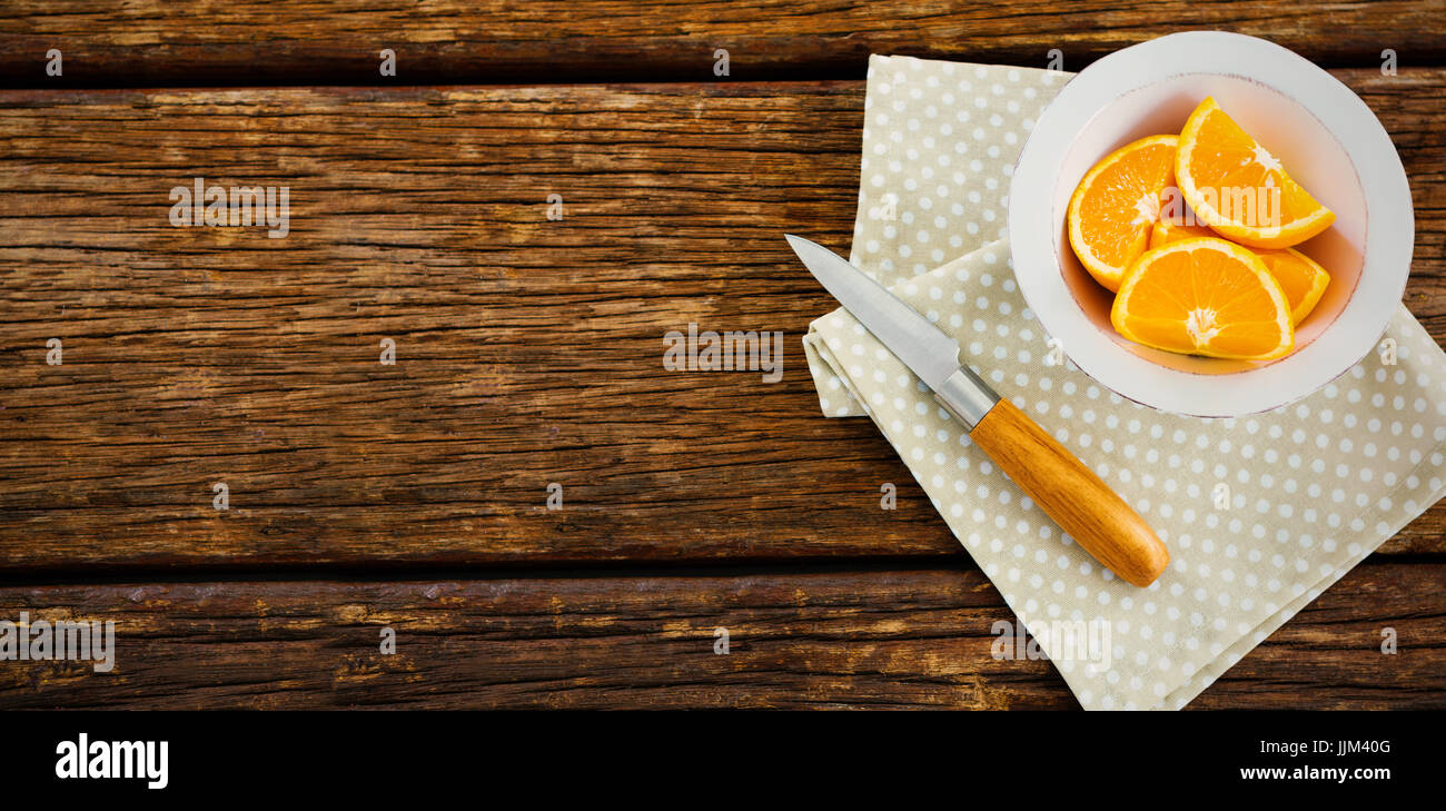 Les tranches d'Orange dans un bol à l'aide d'un couteau et une serviette sur la table Banque D'Images