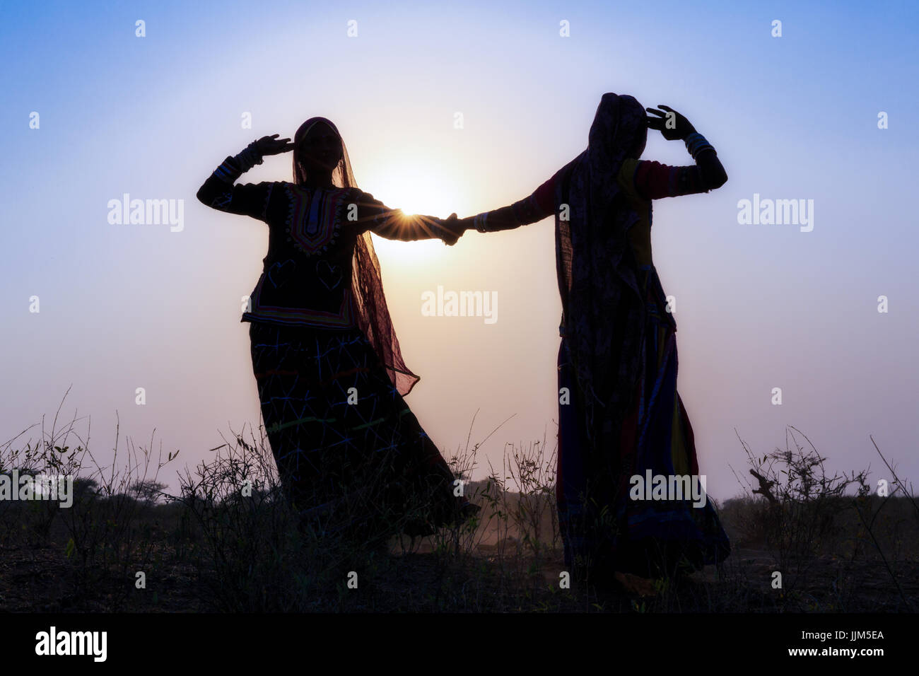 Deux femmes gitanes en robes danser devant le soleil couchant, Pushkar Camel Fair, Pushkar, Rajasthan, India Banque D'Images