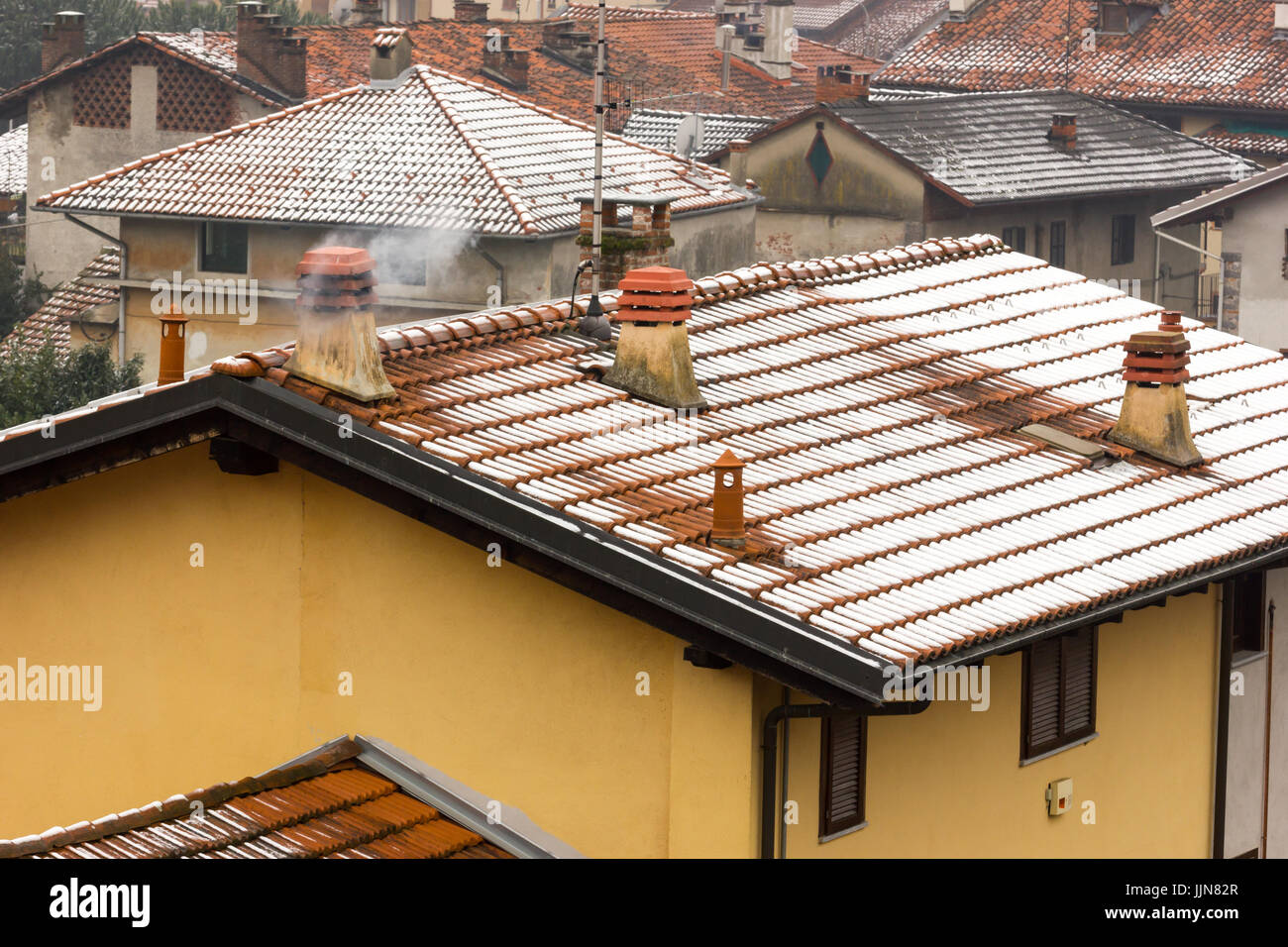 Trois cheminées moderne en béton avec de la fumée qui sort, le toit couvert de neige Banque D'Images