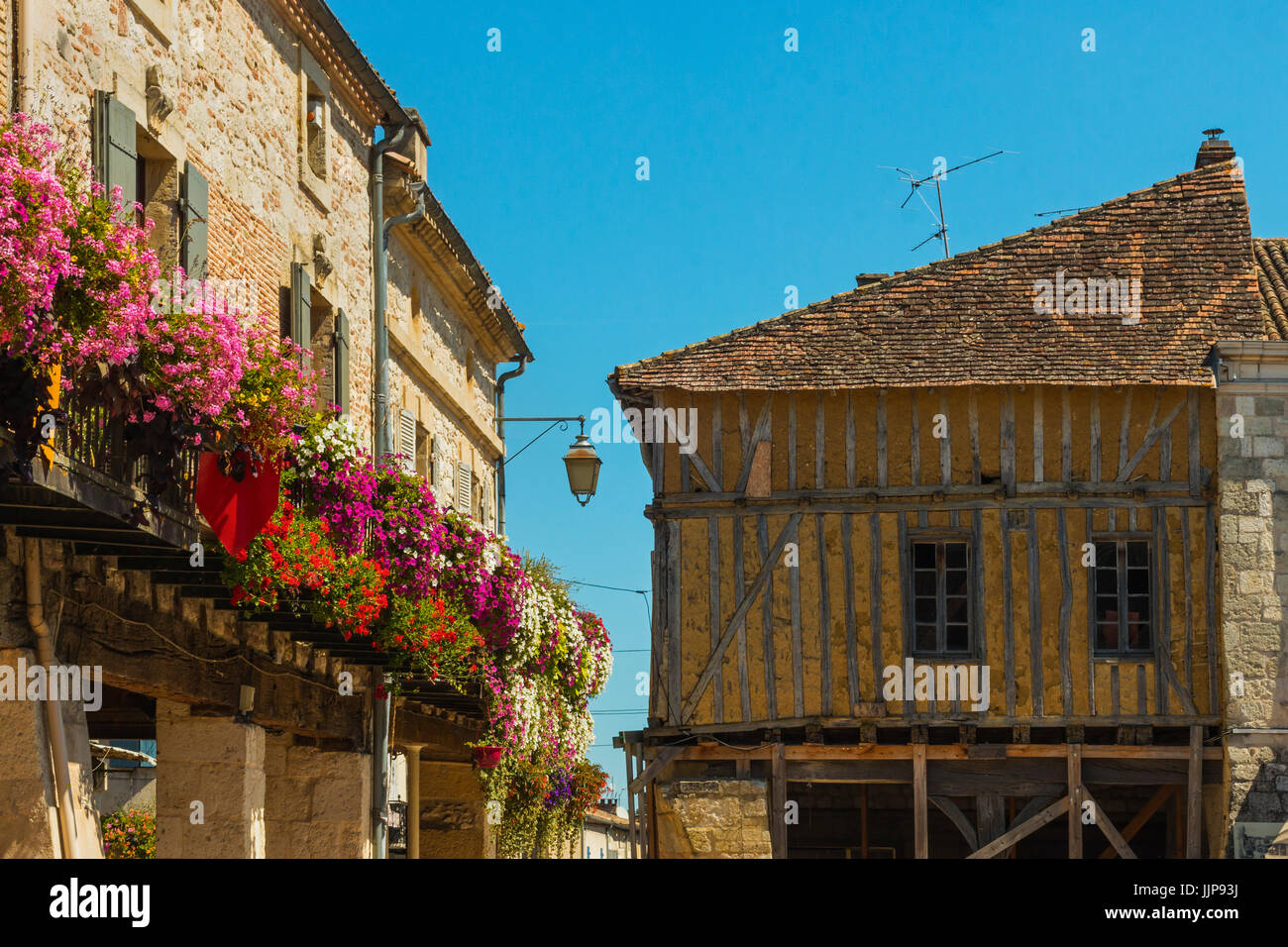 Fleurs et half-timbered édifice médiéval sur la Place de la Halle dans cette jolie ville bastide du sud-ouest. Villereal, Lot-et-Garonne, France Banque D'Images