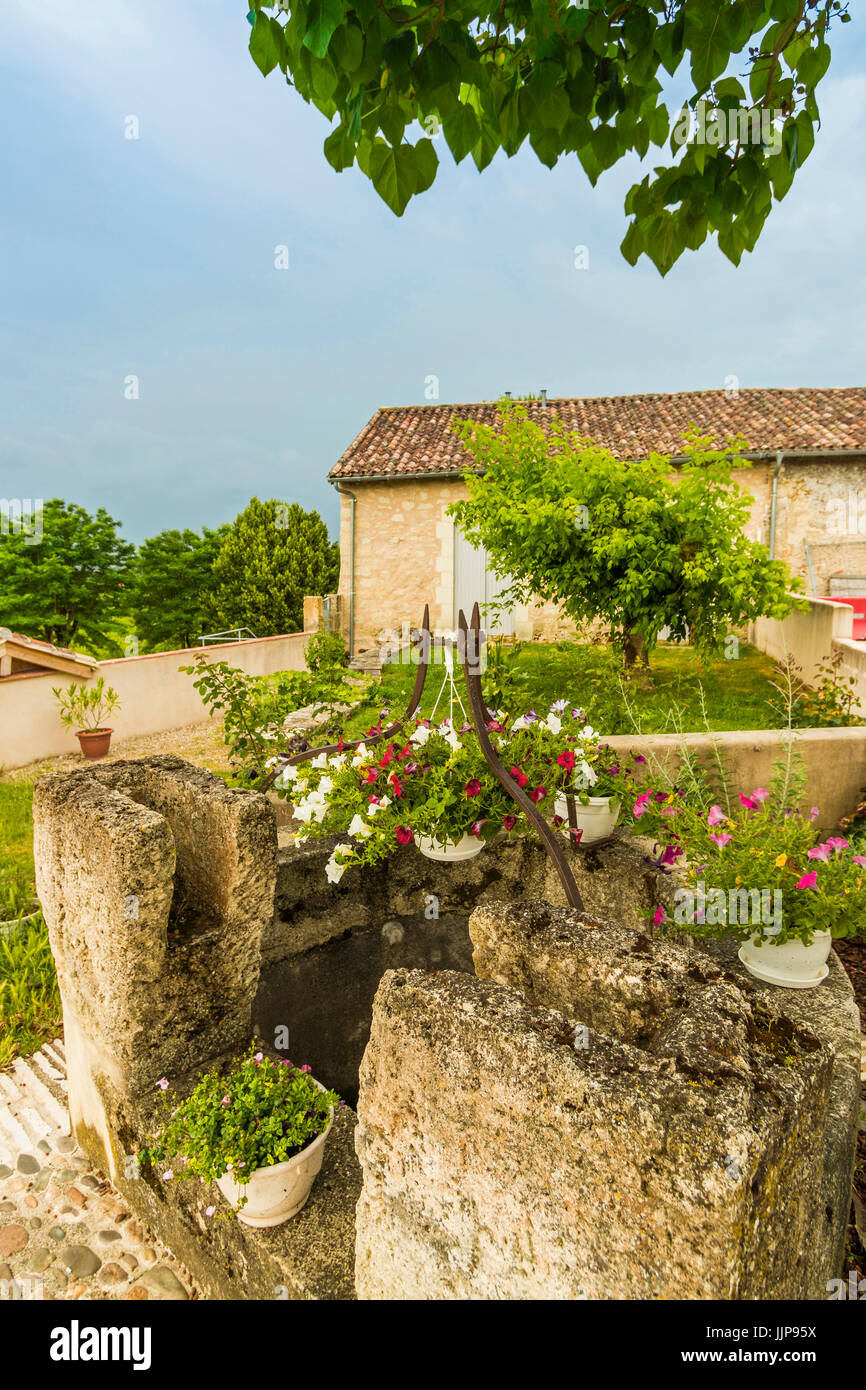 Ancien puits en pierre et des fleurs à ce joli village perché près de Duras ; Monteton ; Lot-et-Garonne, Aquitaine, France Banque D'Images