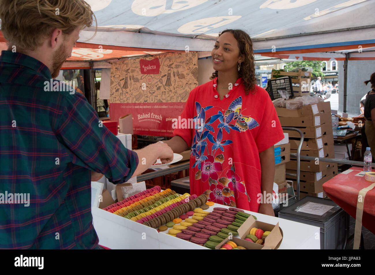 Le vrai marché alimentaire à l'extérieur de la gare de King's Cross, Londres. Ce commerçant vend des macarons Banque D'Images