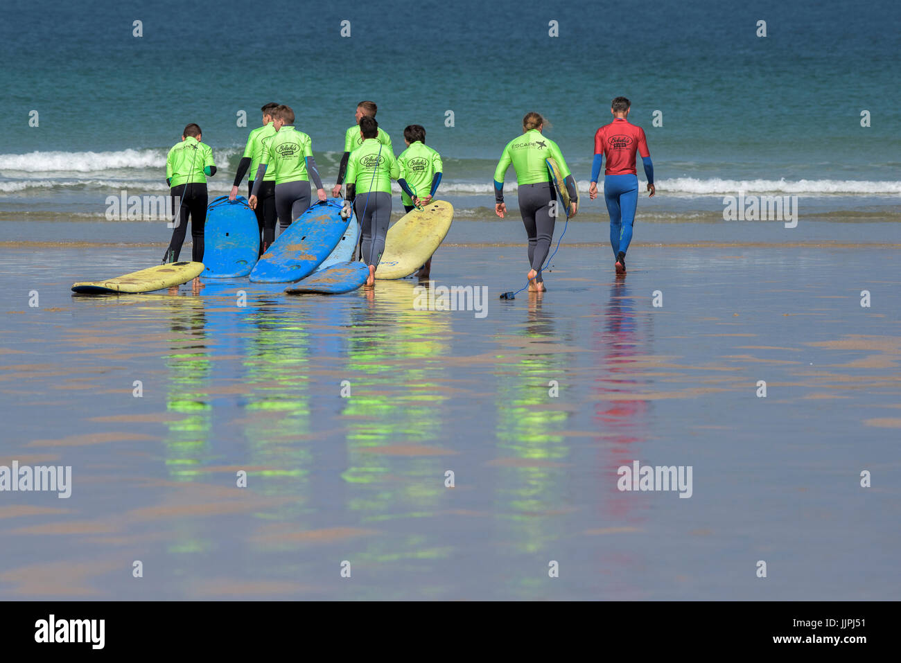 Une école de surf le formateur anime un groupe de novices à la mer à la plage de Fistral à Cornwall. Banque D'Images