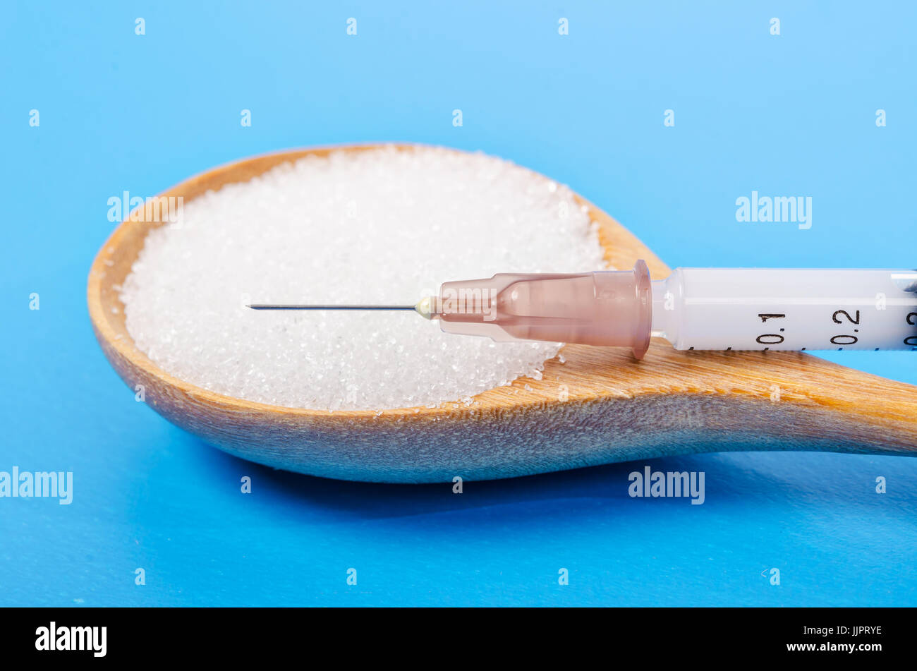 L'insuline dans la seringue et le sucre blanc en cuillère en bois sur fond bleu (diabète) Banque D'Images