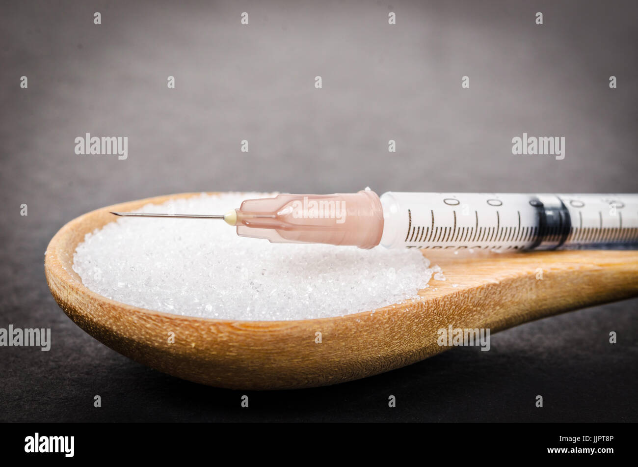 L'insuline dans la seringue et le sucre blanc en cuillère en bois sur fond noir (diabète) Banque D'Images