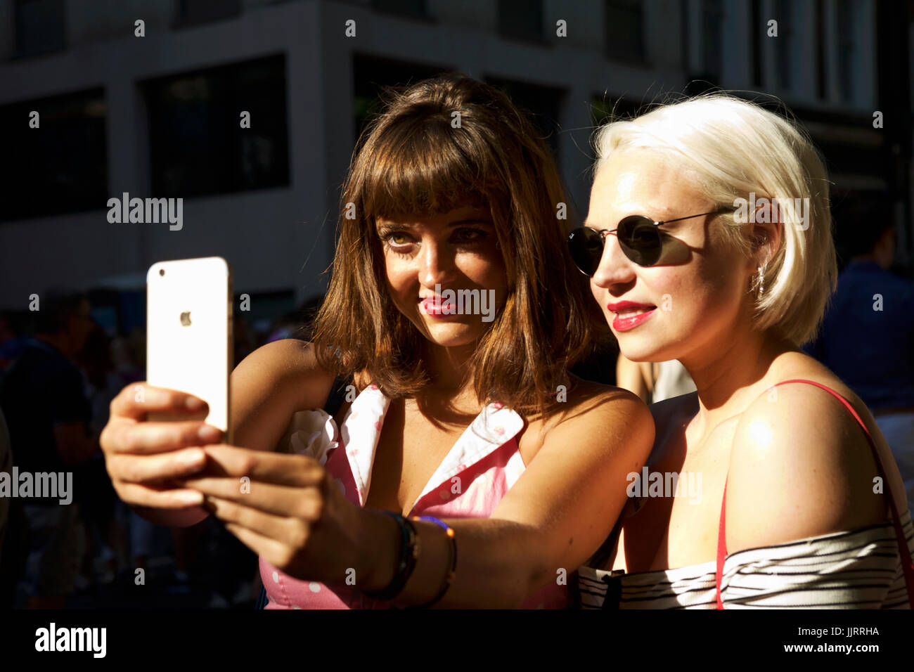 Selfies Smartphone, deux jeunes femmes à la mode d'été vintage prendre un autoportrait, Soho Londres UK London mode rétro. L'appareil photo du smartphone millénaire Banque D'Images