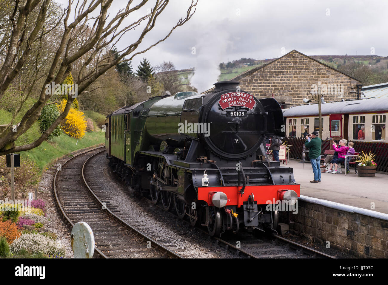 Les gens sur la plate-forme d'emblématique locomotive vapeur 60103 Flying Scotsman en voies souffler la fumée - Keighley et Worth Valley Railway station, Angleterre, Royaume-Uni. Banque D'Images