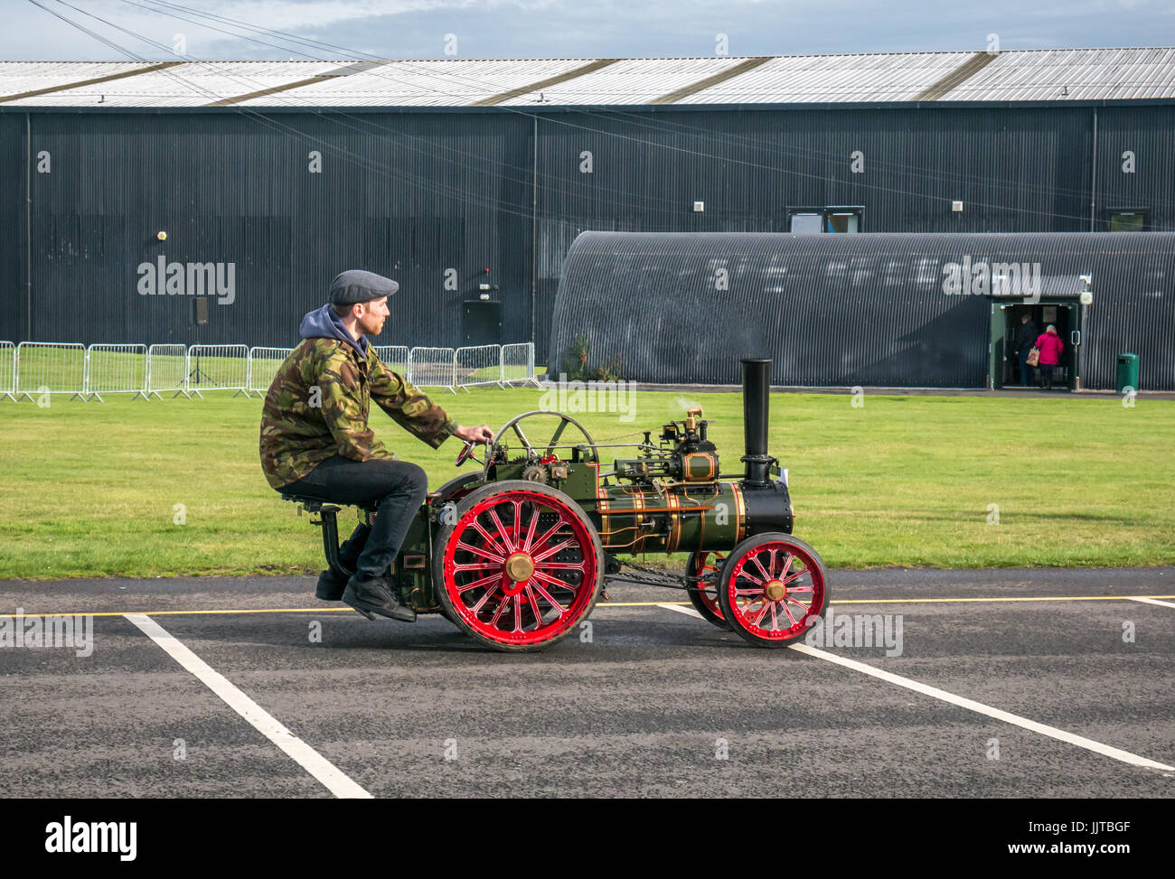 Homme portant un capuchon plat conduisant un moteur de traction à vapeur miniature À l'événement Wheels and Wings 2016 East Fortune East Lothian Banque D'Images