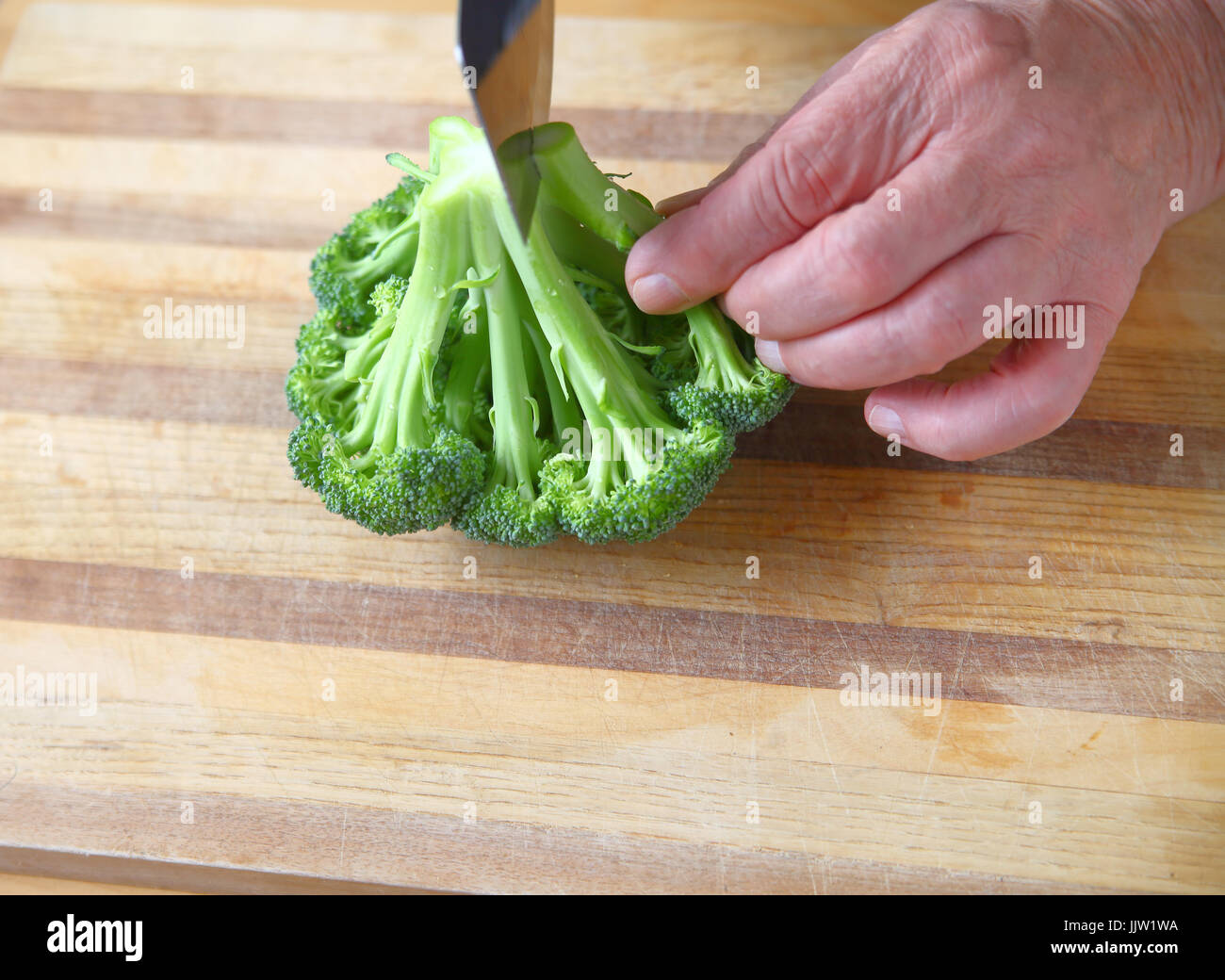 Un homme coupe le brocoli frais sur une planche à découper, place pour le texte Banque D'Images