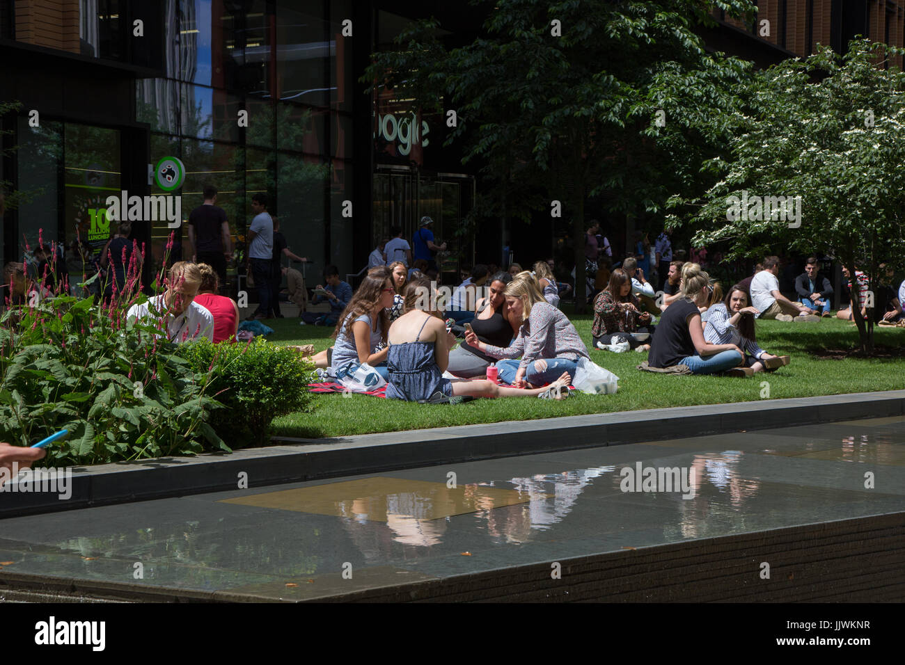 Employés de bureaux sortir pour le déjeuner sur l'herbe à Pancras Square, Kings Cross Banque D'Images