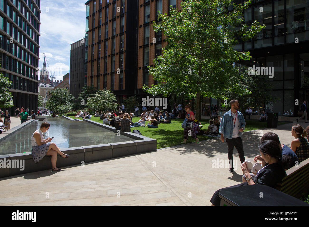 Employés de bureaux sortir pour le déjeuner sur l'herbe à Pancras Square, Kings Cross Banque D'Images