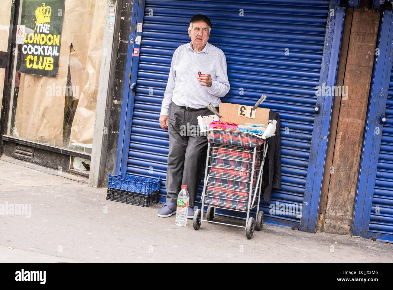 Vieil homme street vendeur vendre fidget spinners en jupon Lane marché plein air, l'un des quartiers les célèbre marché du dimanche dans l'Est de Londres, UK Banque D'Images