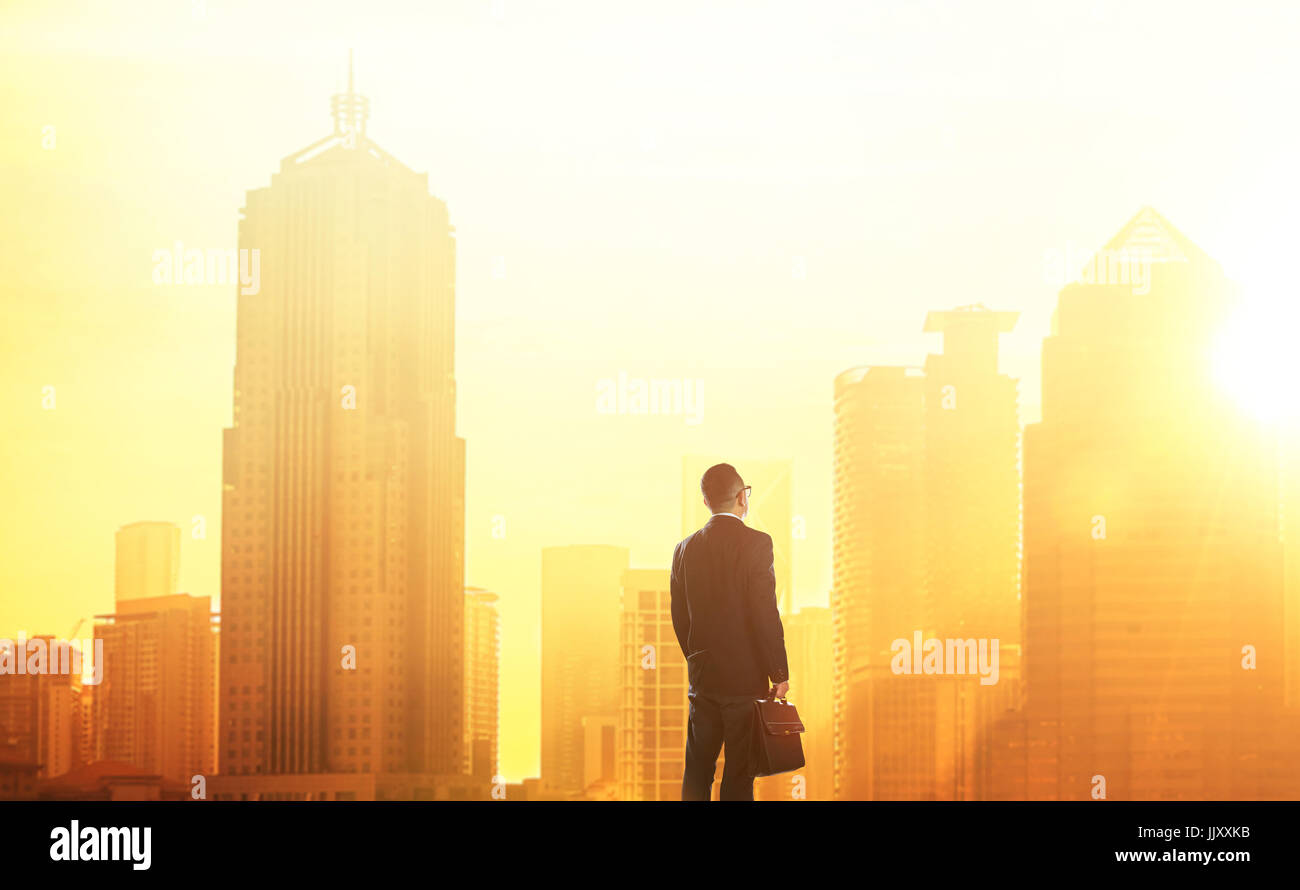 Smart jeune businessman looking at grand centre-ville. Concept de la réussite et de l'appréciation. Debout devant le spectaculaire skyline avec c bondé Banque D'Images