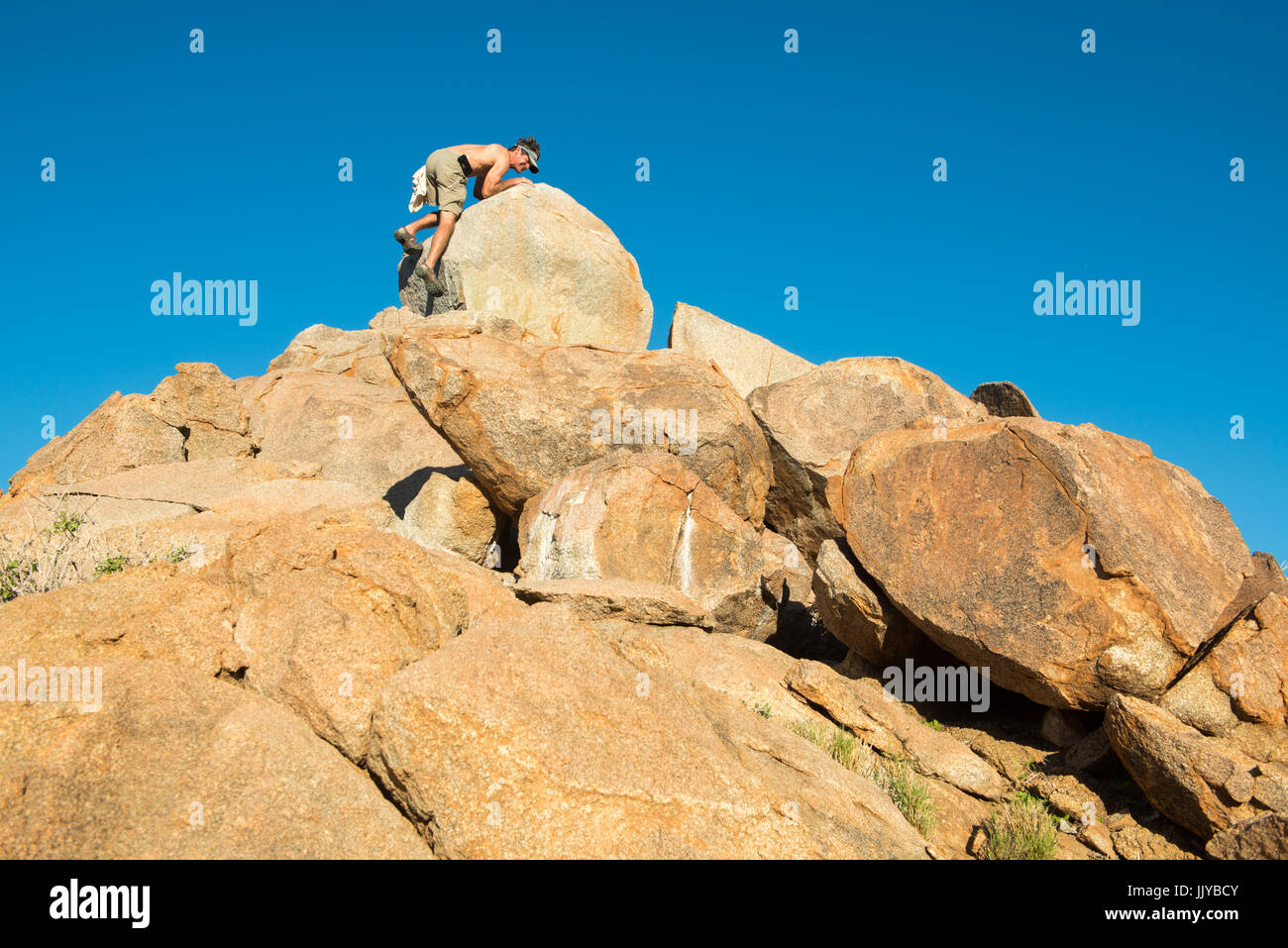 Un touriste est l'ascension d'une grande formation rocheuse dans le Namib-Naukluft National Park en Namibie, l'Afrique. Banque D'Images