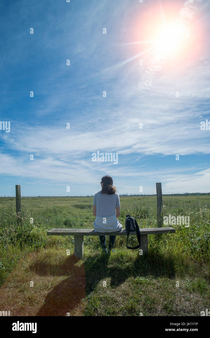 Femme assise sur un banc en bois, enoying la vue dans la campagne Banque D'Images
