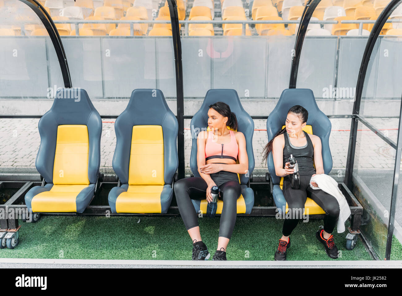 Les jeunes femmes remise en forme fatigué dans les vêtements de sport au repos dans les sièges du stade Banque D'Images