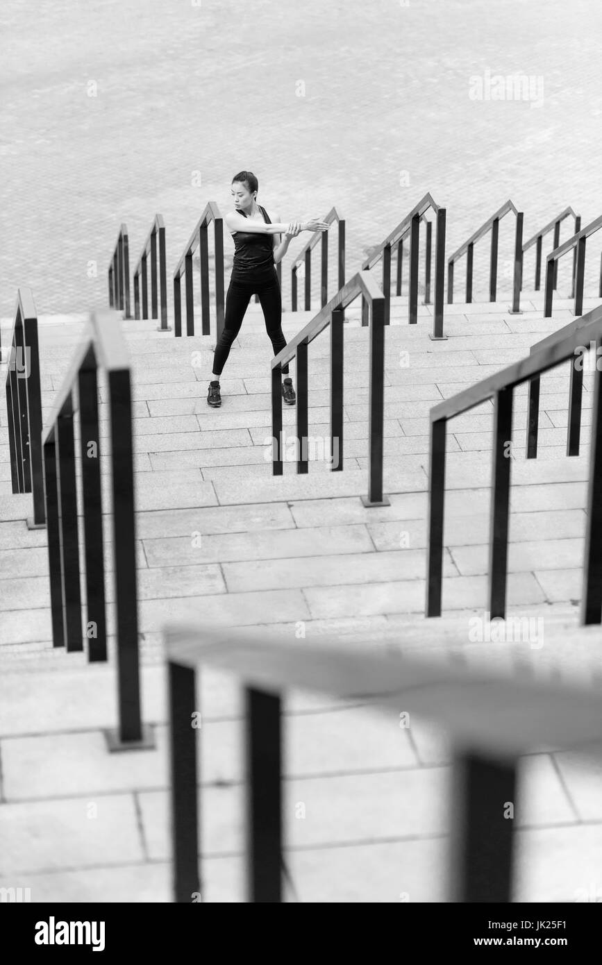 Photo en noir et blanc de jeune femme sportive exerçant sur les escaliers du stade Banque D'Images