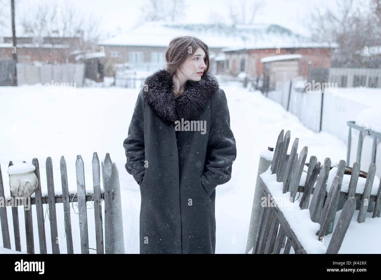 Caucasian woman wearing coat en hiver près de clôture Banque D'Images