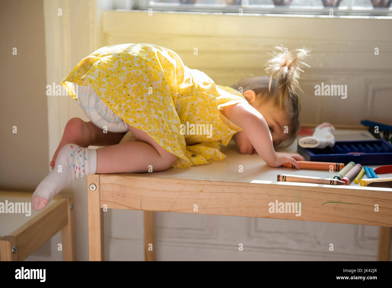 Caucasian baby girl laying on table près de window Banque D'Images