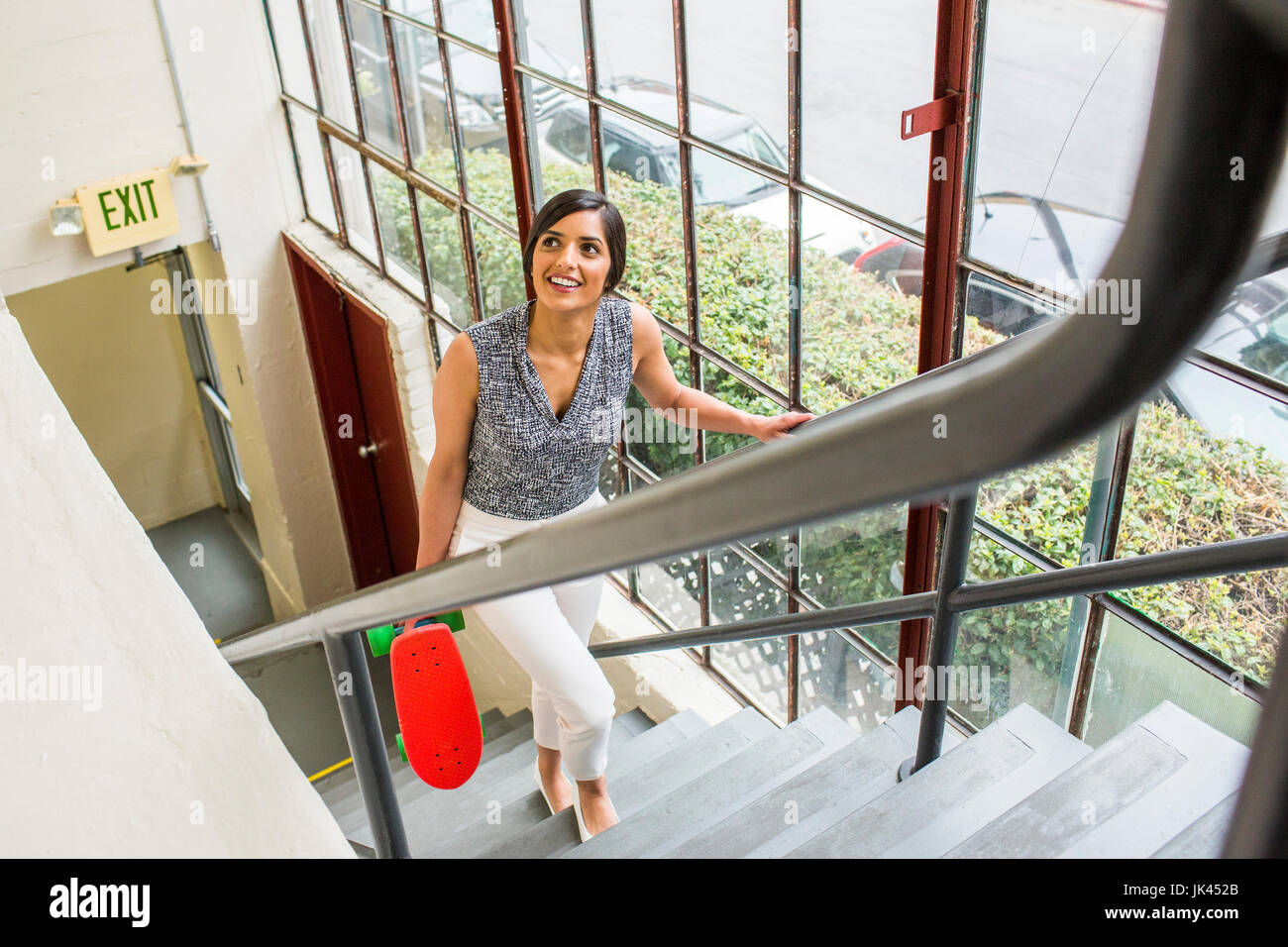 Asian woman carrying skateboard on staircase Banque D'Images