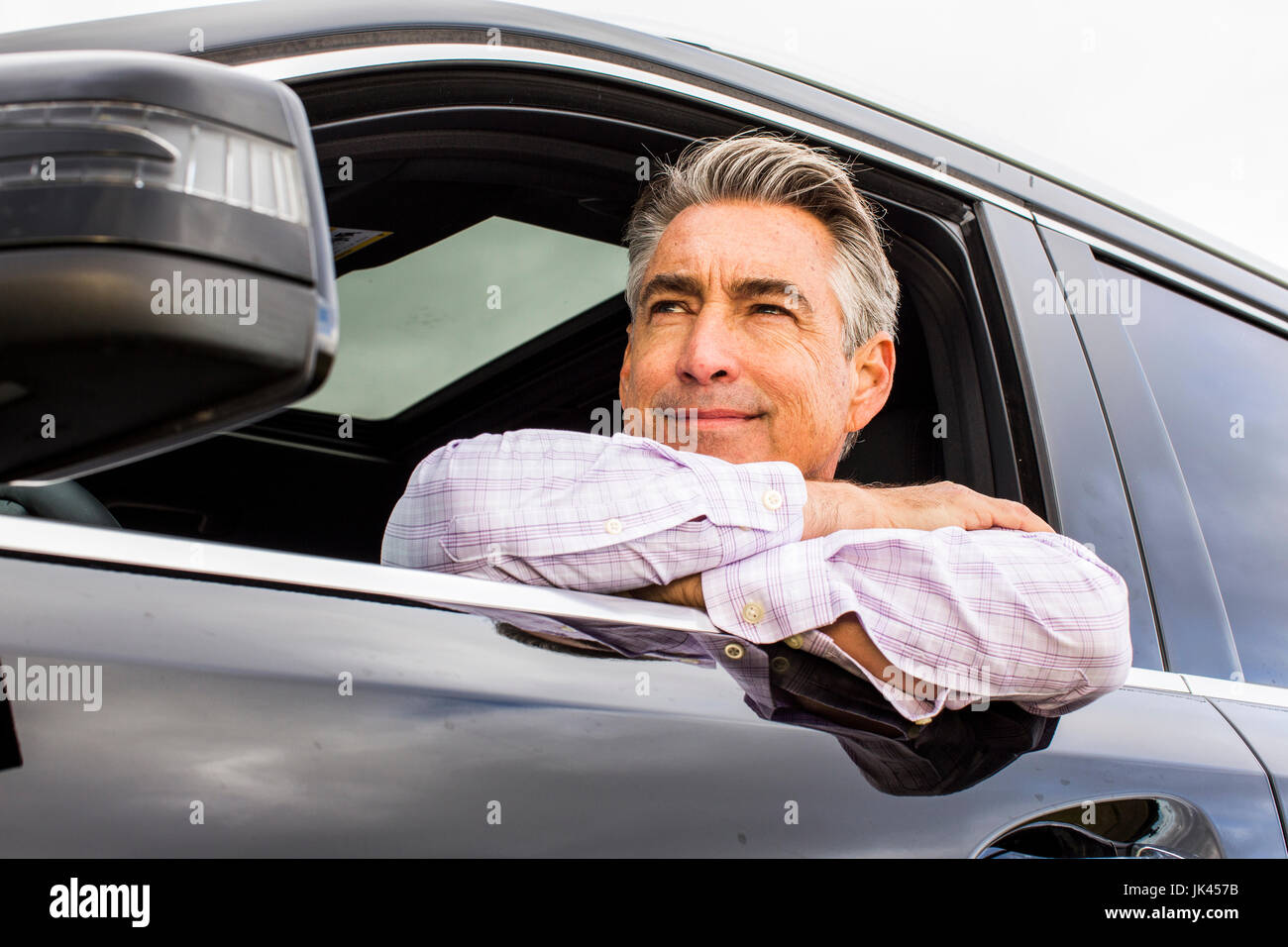 Smiling Caucasian businessman leaning on car window Banque D'Images