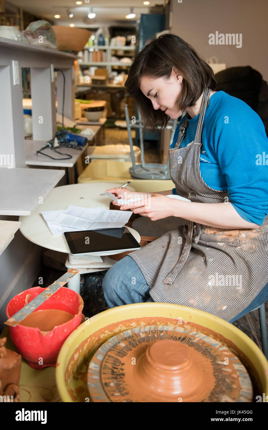 Caucasian woman reading paperwork près de roue de poterie Banque D'Images