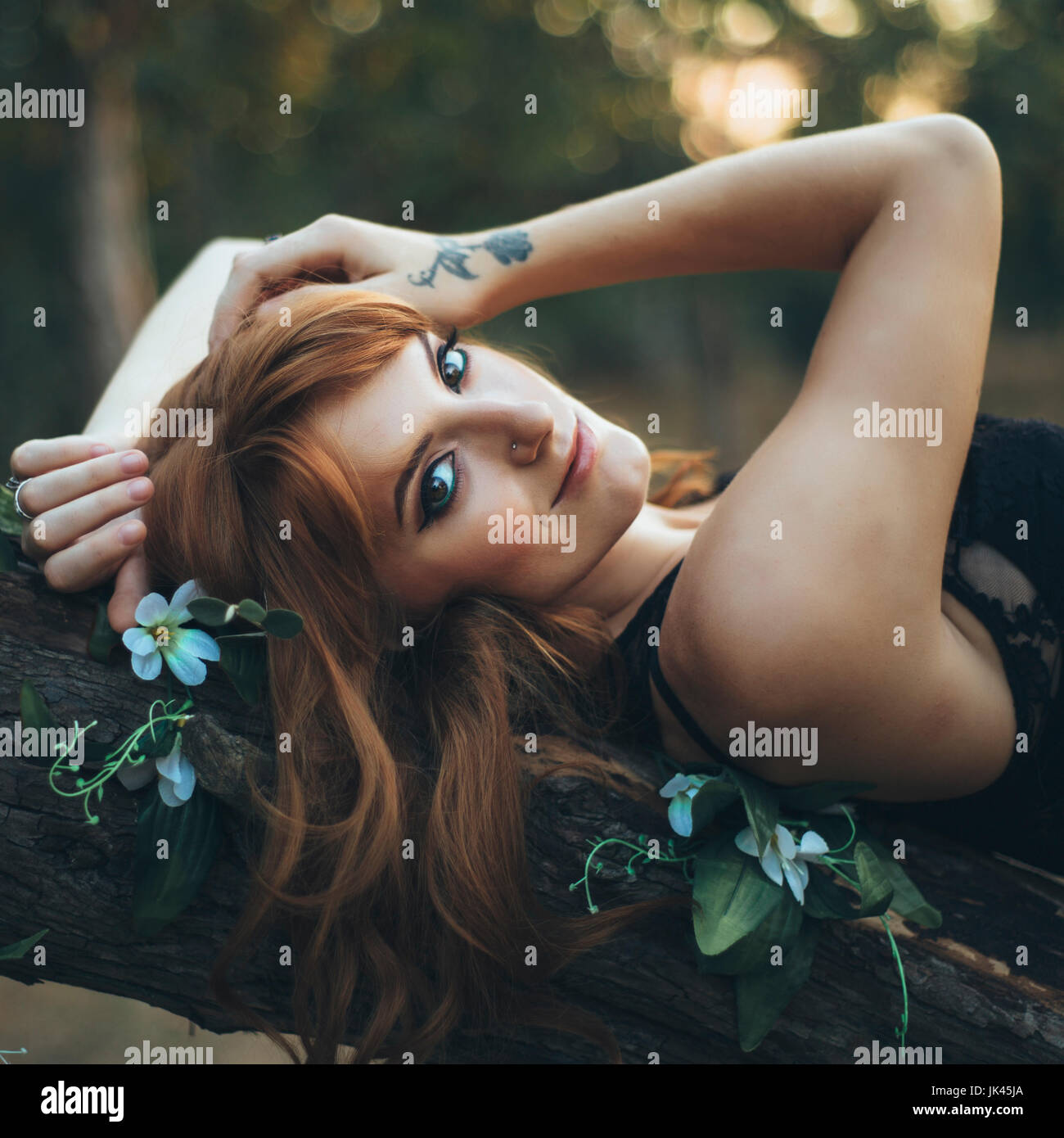 Smiling Caucasian woman laying on tree branch Banque D'Images