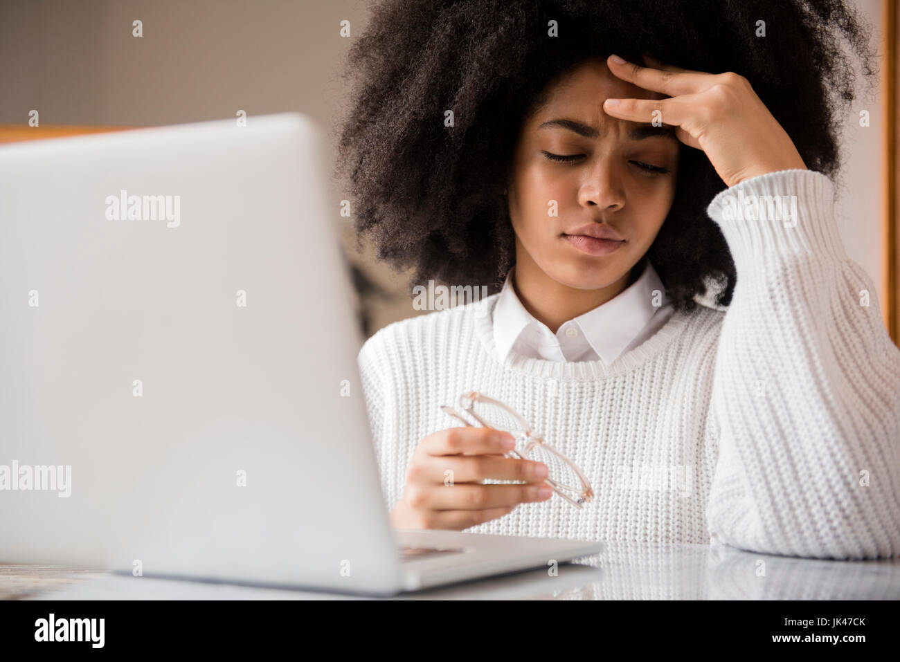 Frustrés African American Woman holding eyeglasses near laptop Banque D'Images