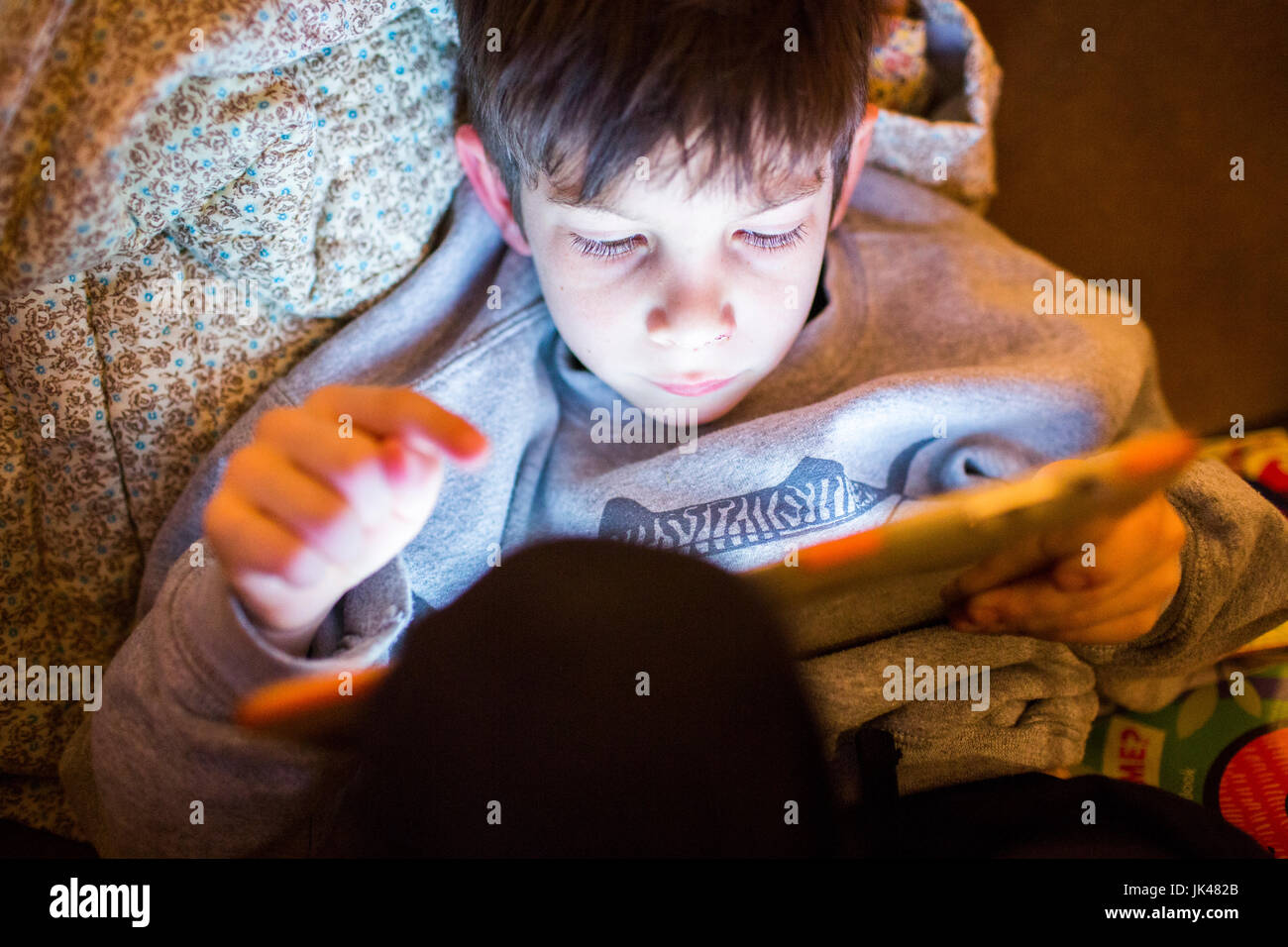 Mixed Race boy using digital tablet at night Banque D'Images