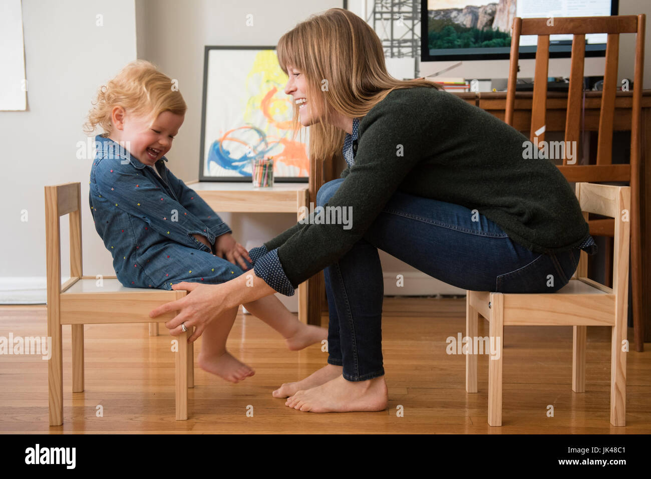 Caucasian mother and daughter sitting sur petites chaises in home office Banque D'Images