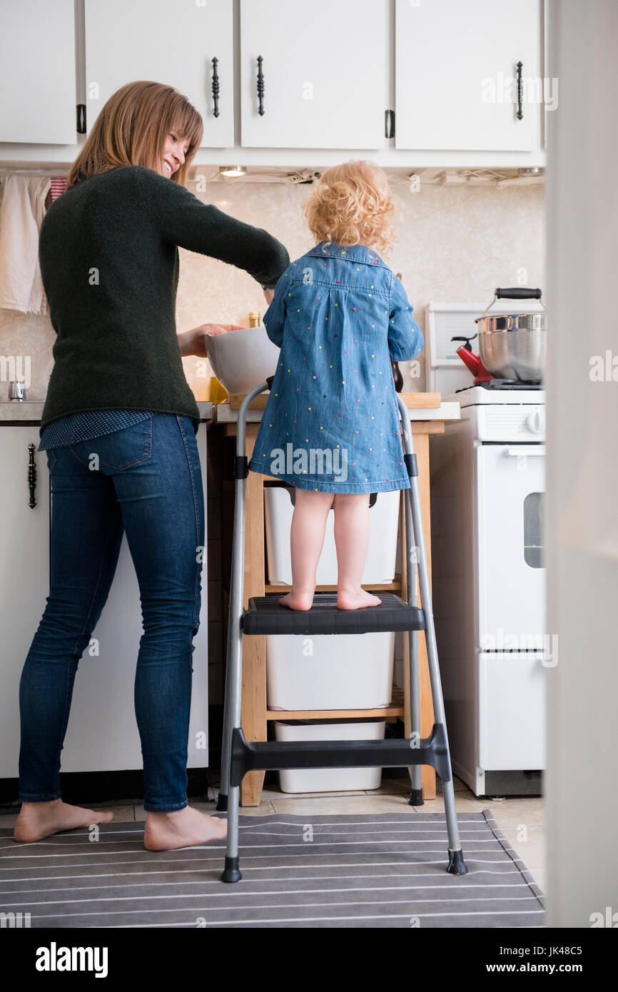 Caucasian Girl standing la cuisson avec la mère dans la cuisine Banque D'Images