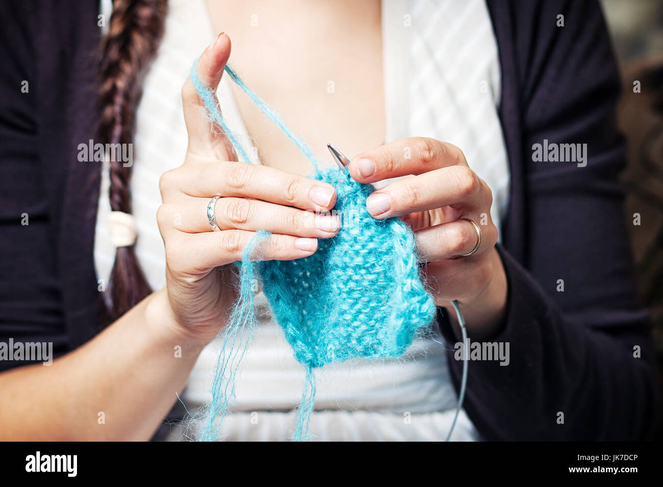 Close-up jeune femme brune avec une queue de cochon avec une profonde coupure sur une maille crochet avec filetage chandail tricoté en laine bleu Banque D'Images
