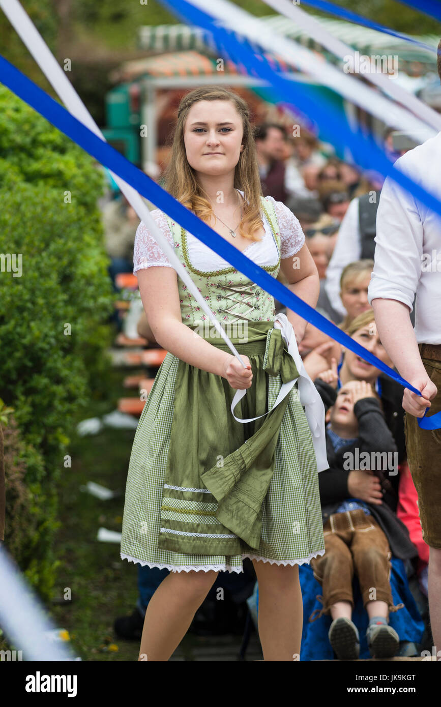 Jeune femme bavaroise traditionnelle en dirndl dress holding ruban blanc lors de l'exécution de la danse folklorique a Bandltanz autour du maypole Banque D'Images