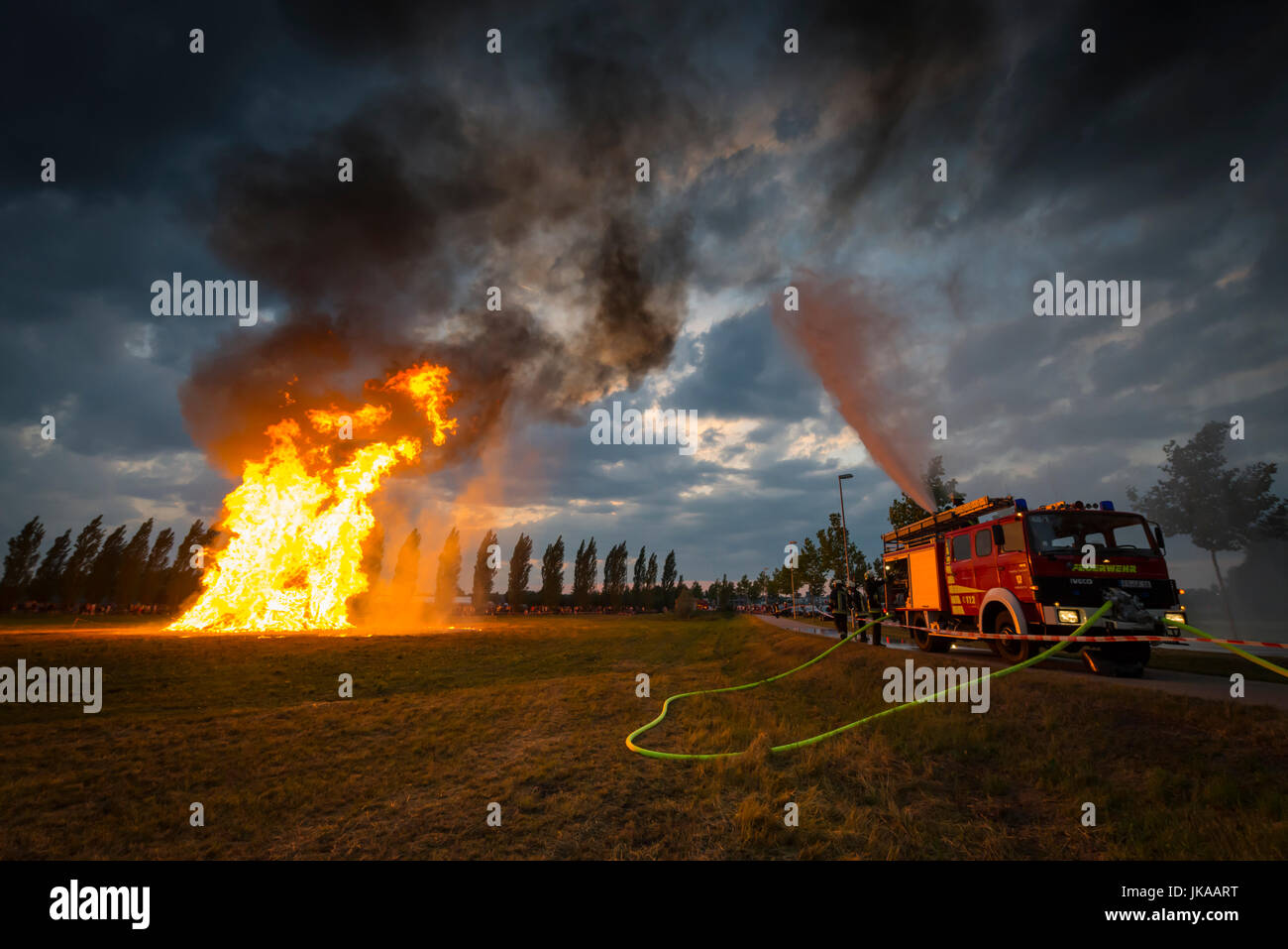 Fire fighter on fire engine l'eau contre les éclaboussures des étincelles de la colonne de feu en direction de célébrations solstice et Midsummer Festival Banque D'Images