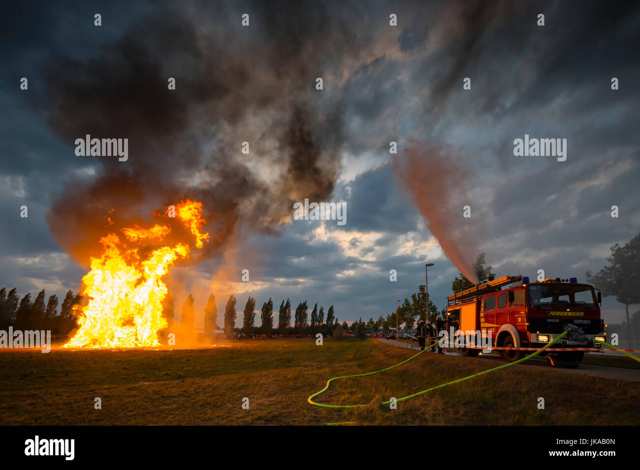 Fire fighter on fire engine l'eau contre les éclaboussures des étincelles de la colonne de feu en direction de célébrations solstice et Midsummer Festival Banque D'Images